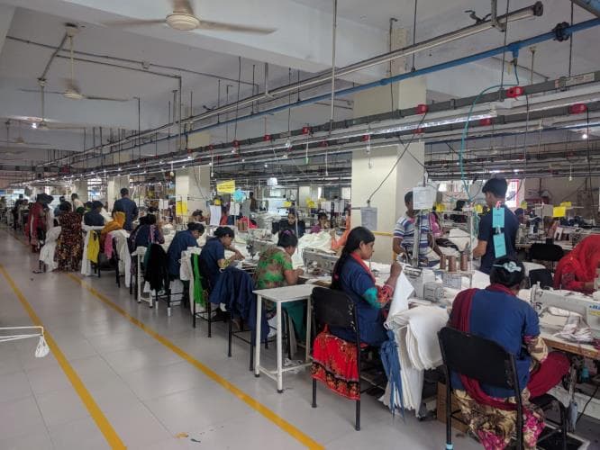 Large-scale garment sewing floor with rows of production workers at industrial machines